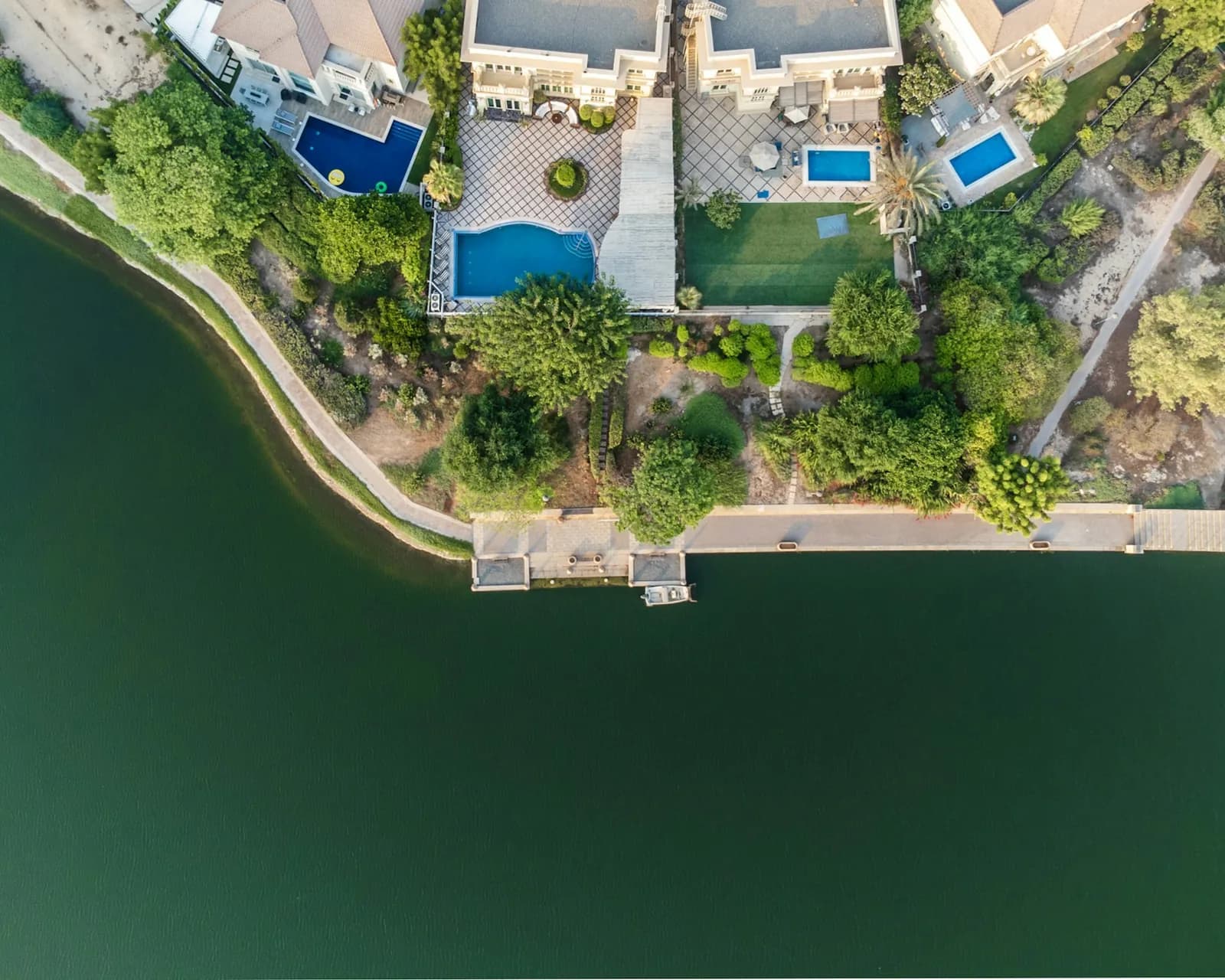 Vista aérea de villas con jardines y piscinas junto al lago en Jumeirah Islands, Dubai
